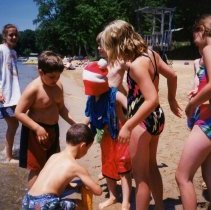 Children sitting and standing on beach.
