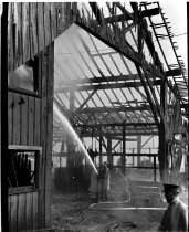 Fireman spraying water on shell of burned building