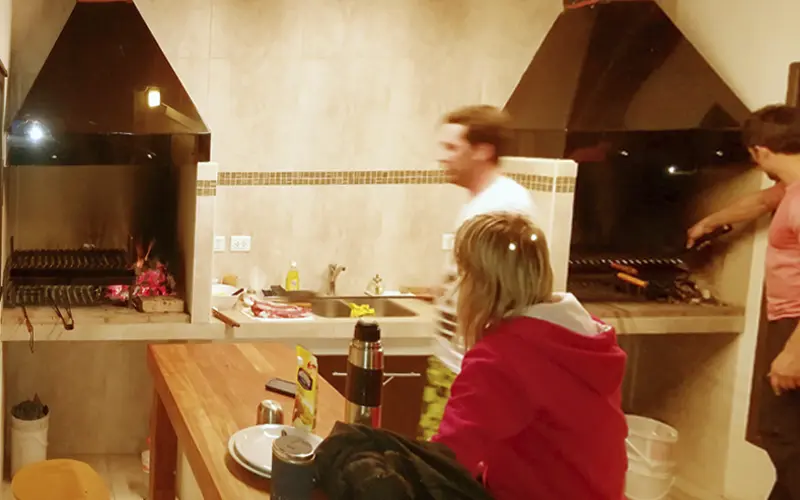 Guests cooking in the covered barbecue area of ​​the Posada El Barranco cabins in El Chaltén
