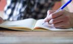 A person using a pen to write in a notebook.
