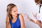 A nurse cleaning a child's upper arm before giving an injection.
