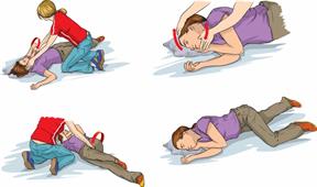 A person helping someone who is on the ground having a seizure. The helper carefully turns the person onto their side.