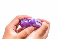 A disk inhaler held in the hands. The lever is being pushed down with the thumb.