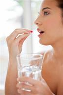 A person holding a glass of water and a pill toward the mouth.