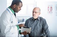 A doctor talking with a person while showing the person information on a computer tablet.