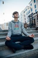 A teenager meditating outdoors while listening to music.