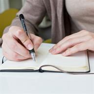 A person using a pen to write in a notebook.