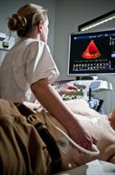 A health care provider holding a wand on a person's chest and looking at a monitor during an echocardiogram.