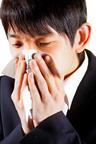 A child holding a cloth over the mouth and nose while sneezing.