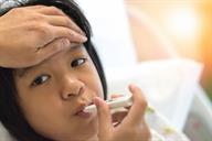 A person putting a thermometer in a child's mouth to take their temperature.