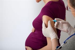 A pregnant person receiving a shot in the upper arm.