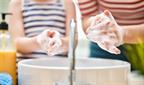 An adult and child washing their hands together over a sink.