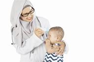 A person holding a forehead thermometer to a baby's head.