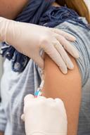 A person receiving a shot in the upper arm.