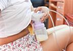 A person using an electric breast pump to express milk into a bottle.