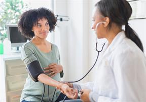 A health care provider taking a pregnant person's blood pressure and pulse.