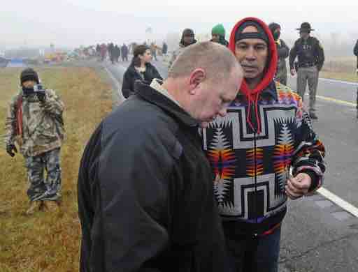 Caption: Morton County Sheriff Kyle Kirchmeier, front, listens to Brian Wesley Horinek, of Oklahoma, outside the New Camp on Pipeline Easement in North Dakota. AP photo