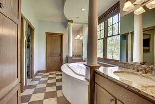 Column framed tub area flanked by his and hers vanities with integral bowl labs and granite countertops.