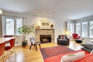 The Light-Filled Living Room features a Gas Fireplace, Gleaming Hardwood Floors, Large Windows and Directional Art Lights...