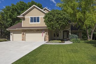 Concrete drive way, lush landscaping, and mature trees