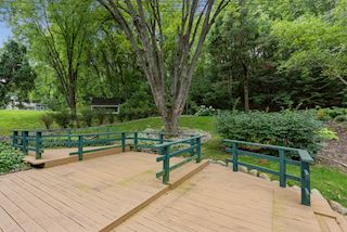 Beautiful back yard with deck, trees and garden landscaping.