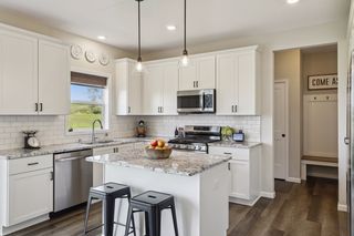 This sensible yet stylish kitchen features granite countertops, white painted cabinetry, stainless steel appliances, subway tile backsplash and upgraded fixtures.