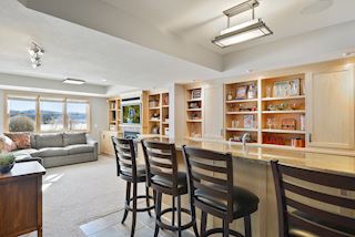 Granite wetbar with mini fridge, built in shelves and TV in bar area