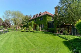 The sweeping front lawn of this magnificent home is surrounded by a black iron fence. 