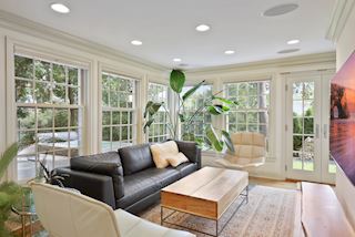Family room with windows and doorway to outdoor decking, resistance pool and jacuzzi and expansive and lush backyard