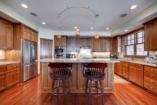 Large granite island work surface with custom art glass lighting above.