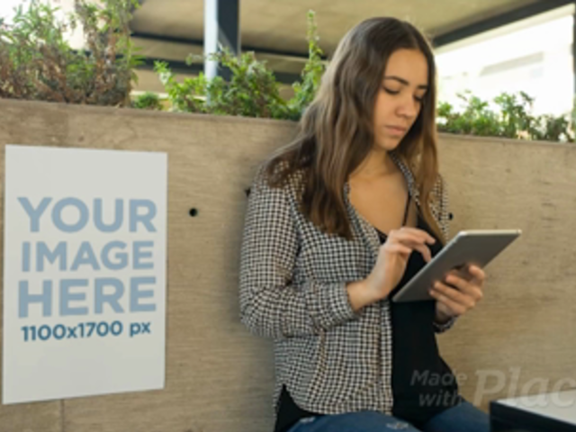Young Business Woman Using An iPad With A Poster Video Mockup Besides Her a13888