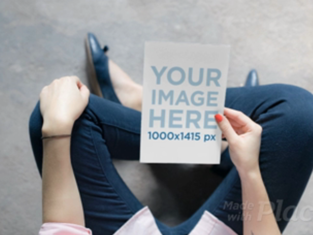 Teenager Girl Holding a Flyer Video Mockup While Sitting In A Concrete Floor a13922