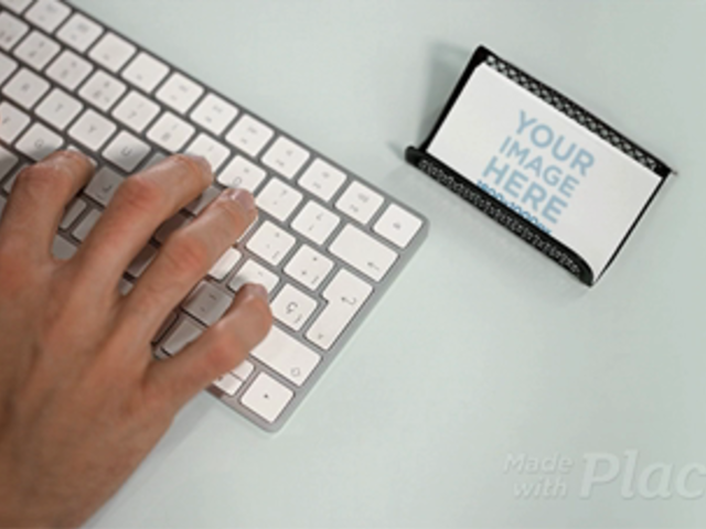 Business Card Lying in a Holder on a Desktop While a Man is Typing a Keyboard in Stop Motion a13727