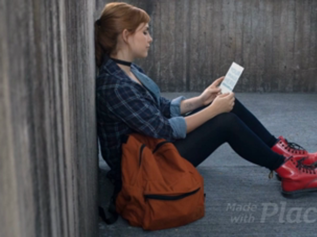 Pretty Redhaired Girl Sitting Down While Holding A Flyer Video Mockup a13896