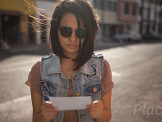 Young Trendy Girl Showing You a Flyer in Stop Motion While on the Street a13739