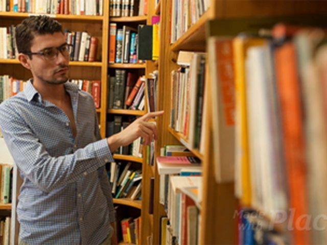 Young Dude Picks Up a Book From a Bookshelf at the Library and Looks At It in Stop Motion a13852