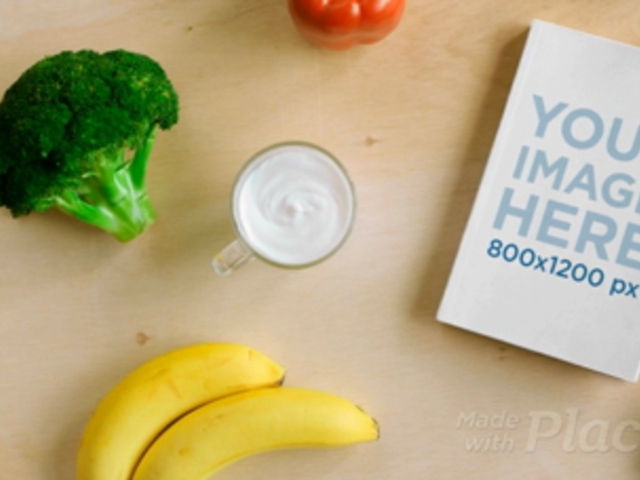 Video of a Book on a Wooden Table with Water Vegetables and Fruits Surrounding It a14177