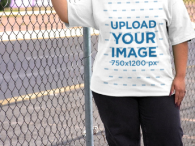 Yazbeck T-Shirt Mockup Featuring a Serious Woman Posing Against a Wire Fence 7620v