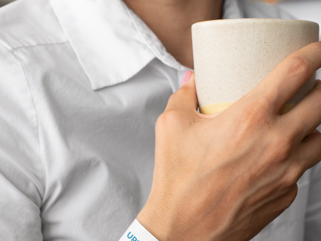 Placeit - Paper Wristband Mockup Featuring a Woman Holding a Coffee Cup