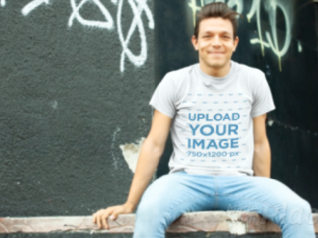T-Shirt Video of a Man Sitting on a Wooden Platform Against a Graffiti Wall 13031