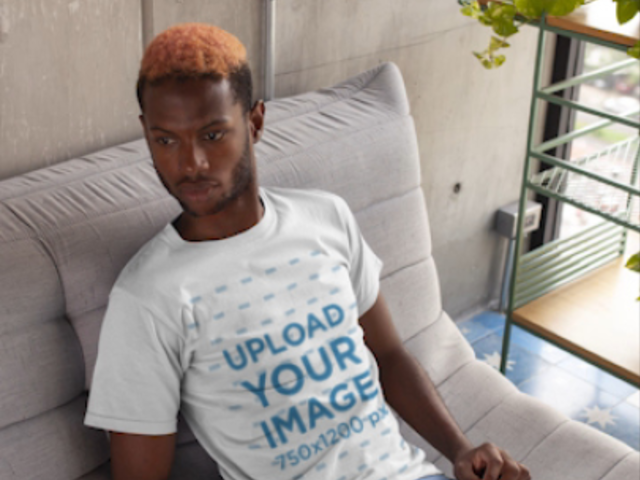  T-Shirt Video of a Serious Man Sitting on a Grey Fabric Couch 22542