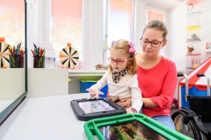 Non-verbal girl living with cerebral palsy, learning to use digital tablet device to communicate. People who have difficulty developing language or using speech use speech-generating devices. speech therapy AAC