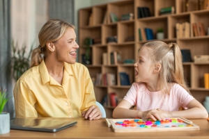Speech training for kids. Professional female specialist training with girl, teaching kid right articulation exercises speech therapy articulation