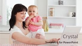  Presentation with baby sitting - Presentation having cute brunette woman relaxing with her laptop next to her baby while sitting in the kitchen background and a soft green colored foreground