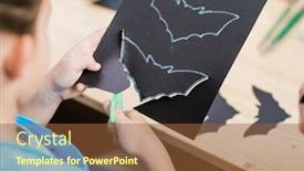  Presentation with halloween bat - Cool new slide deck with hands of elementrary pupil cutting out halloween bat from black paper while sitting by wooden desk at lesson backdrop and a tawny brown colored foreground