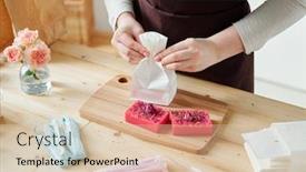  Presentation with making soap - Cool new theme with hands of girl packing pink handmade soap bar into paper packet on wooden board while making gifts for friends backdrop and a lemonade colored foreground
