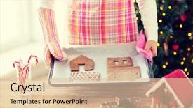  Presentation with christmas baking - Audience pleasing presentation theme consisting of holidays christmas baking and sweets concept - closeup of woman holding pan with gingerbread house details on it at home backdrop and a lemonade colored foreground