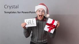 Presentation with text box - PPT theme featuring image of young happy man wearing christmas santa hat standing isolated over grey wall holding paper with sale text and gift box looking camera background and a light gray colored foreground