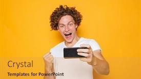  Presentation with joyful - Amazing theme having joyful man 20s with brown hair screaming and clenching fist while taking selfie on mobile phone isolated over yellow background backdrop and a gold colored foreground