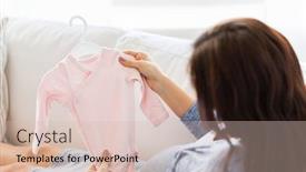  Presentation with motherhood - Audience pleasing PPT theme consisting of motherhood pregnancy people and kids clothing concept - close up of happy woman holding and looking at pink baby girls bodysuit at home backdrop and a soft green colored foreground